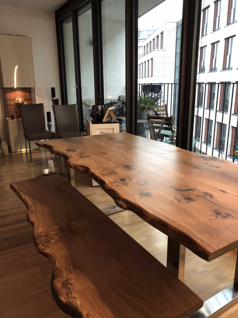 Baumkanten-Esstisch aus Roseneiche vor bodentiefen Fenstern in einem Hamburger Penthouse